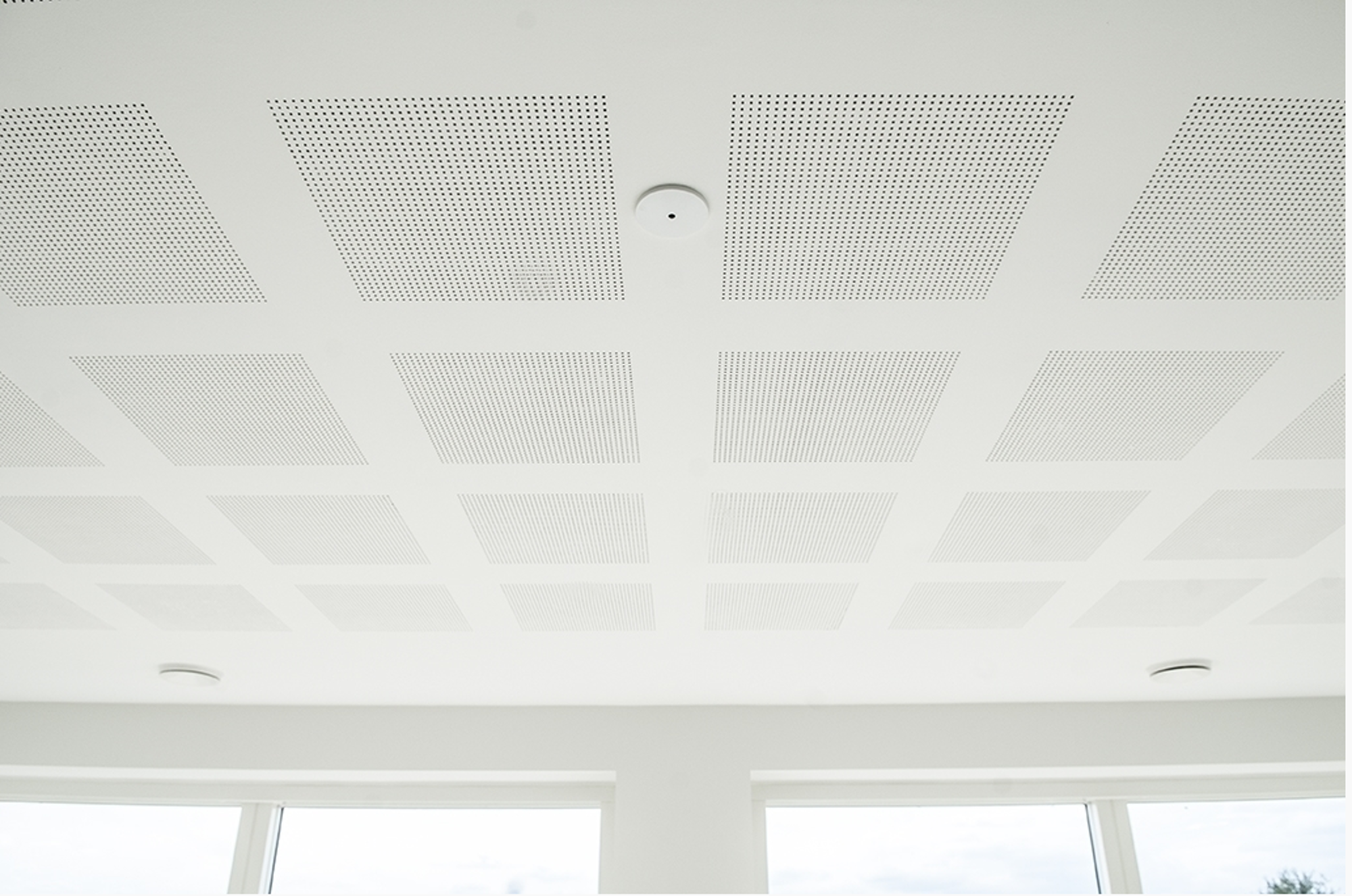 Akustikloft i gips med perforerede felter, indbygget røgalarm og downlights i lyst rum